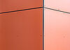 Nahaufnahme einer orangenen Fassade mit Nieten